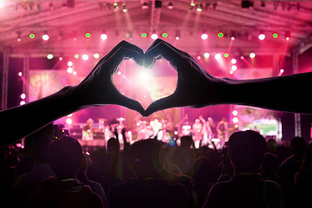 crowd of people at during a concert with a heart shaped hand shadow male and female